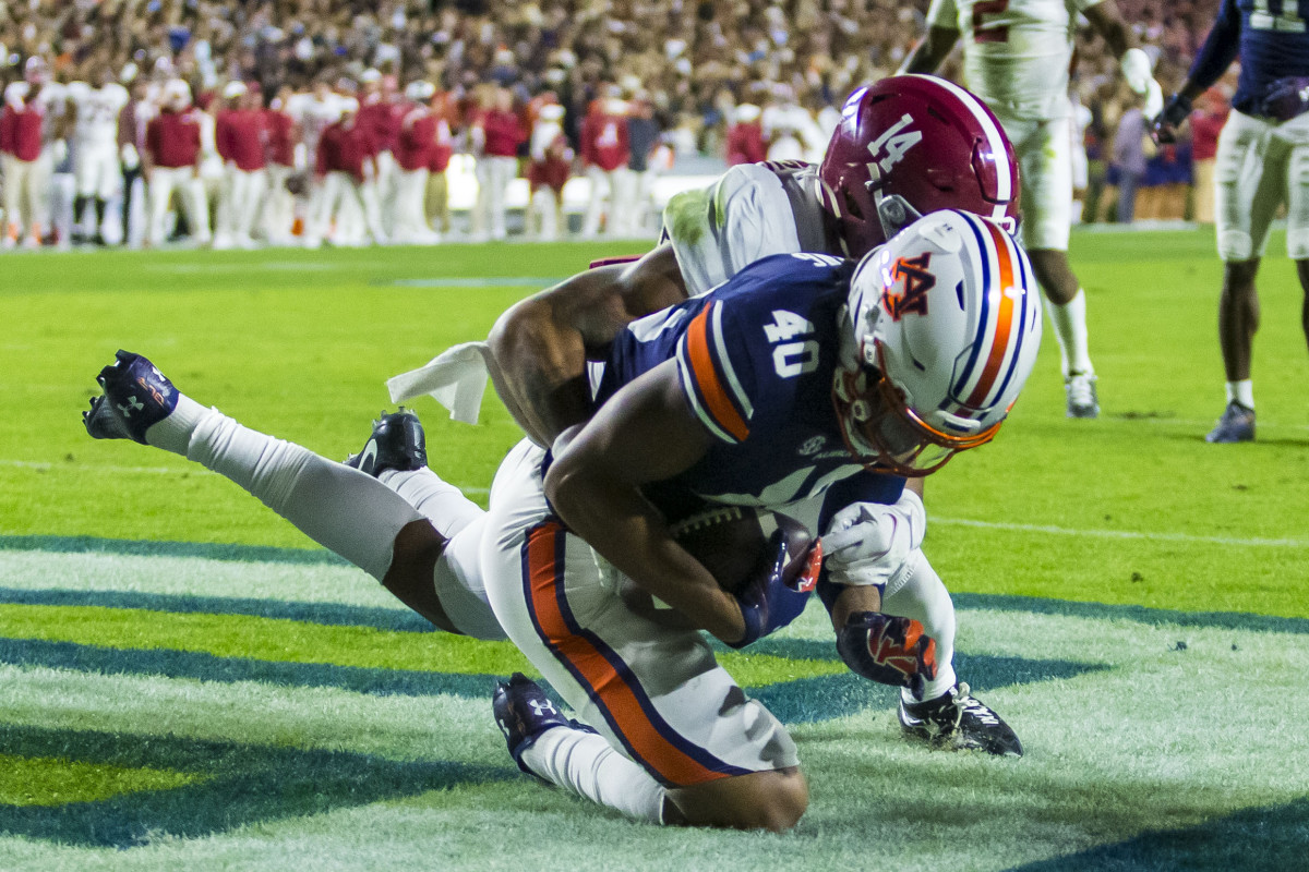 Auburn tight end Landen King (40) makes a one-handed grab to score a touchdown despite Alabama defensive back Brian Branch (14) holding his left arm during the first overtime of an NCAA college football game, Saturday, Nov. 27, 2021, in Auburn, Ala. The touchdown sent the game to a second overtime, a game won in four overtimes by Alabama, 24-22.